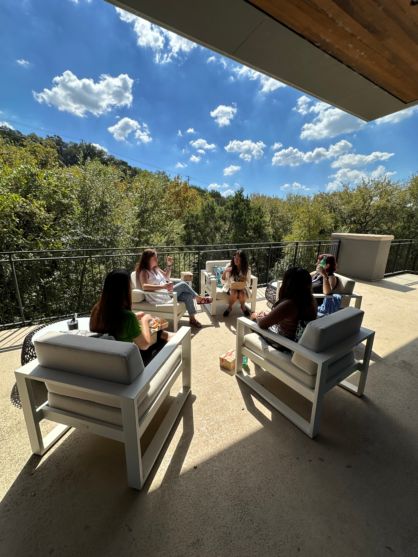 Small-group community conversation happening outside on a sunny terrace